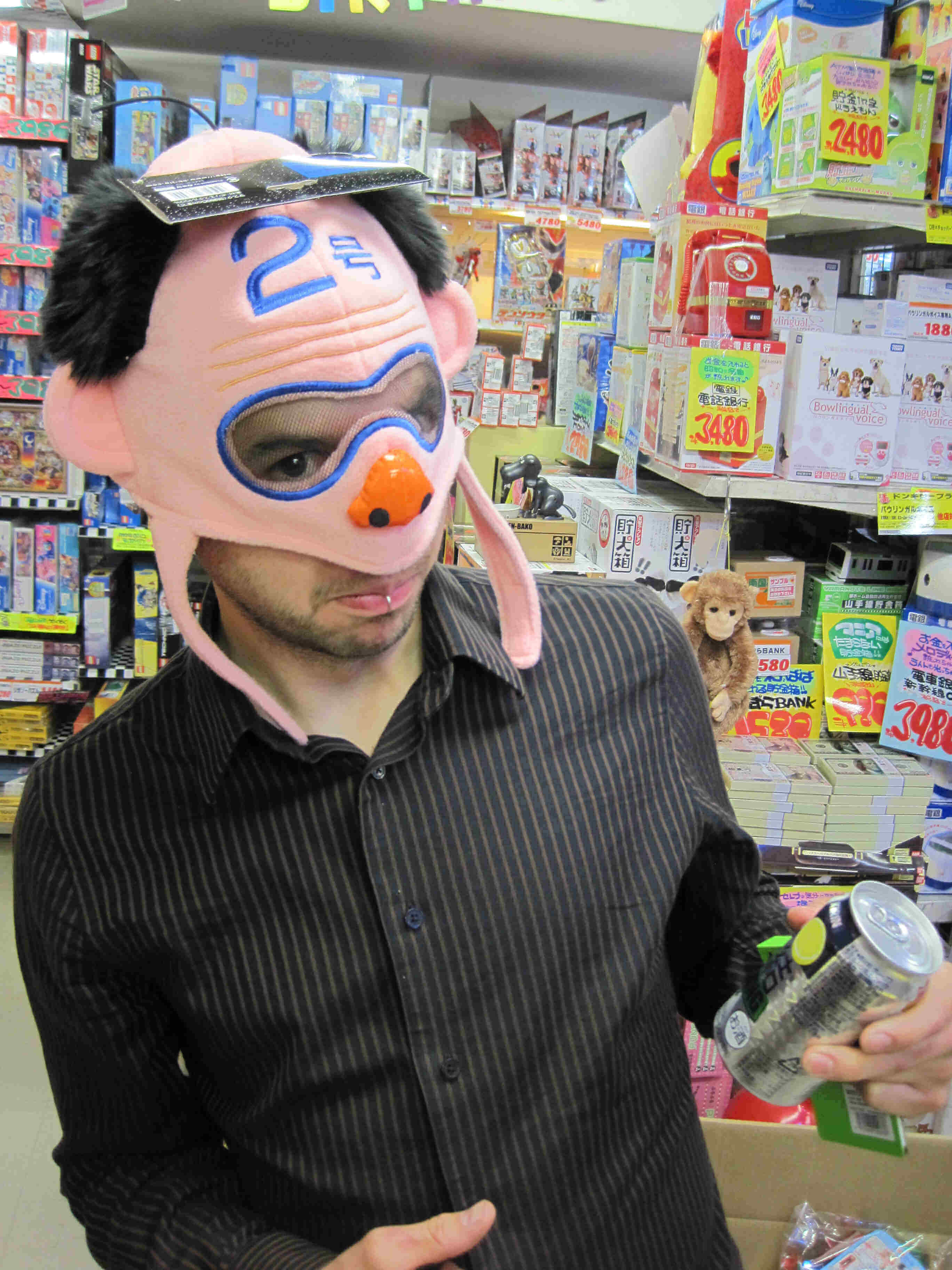 Front view of a person in a Japanese retail store, wearing a costume pig head mask over their head